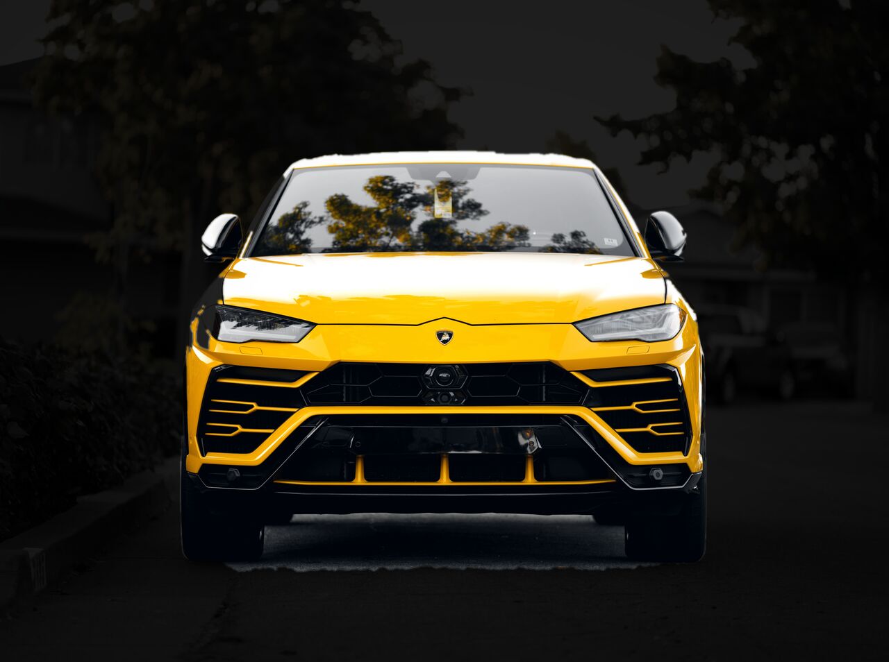 Lamborghini Urus amarelo visto de frente, com os faróis acesos à noite
